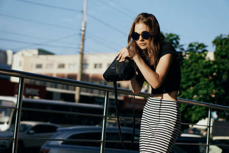 Young beautiful woman in sunglasses and in a skirt on a street in the city.の写真素材