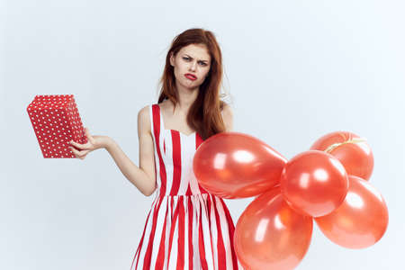 Woman on a light background holds balloons, gift, holiday, emotions.の写真素材