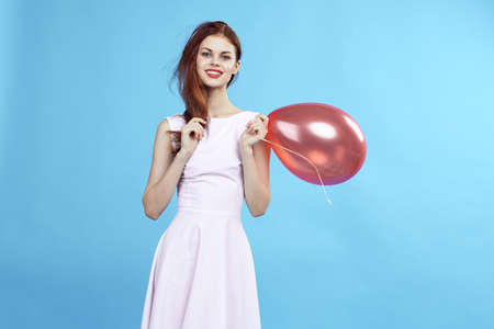 Beautiful woman on a blue background in a dress holding a balloon.の写真素材