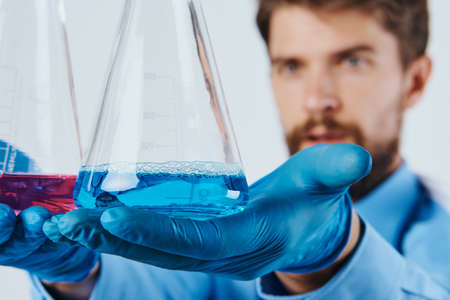 Man with a beard on a light background holds a laboratory glassware, science, doctor, portrait.