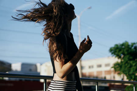 Beautiful woman in sunglasses outdoors in the city, wind, silhouette, portrait.の写真素材