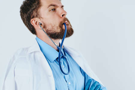 Man with a beard against a light background, stethoscope, medical clothes, doctor, medicine.