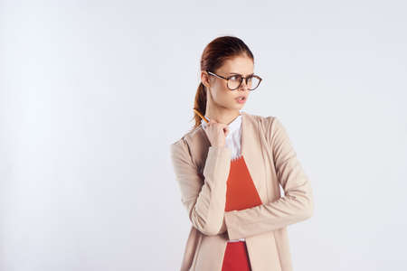 Beautiful young woman on a light background with glasses holding documents, teacher, portrait, blank space for copy.の写真素材