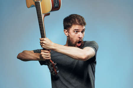Man with a beard on a blue background swings a guitar, emotions, a musician.の写真素材