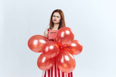 Beautiful young woman on a white background holds balloons and a gift.の写真素材
