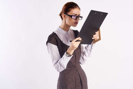 Beautiful young woman with glasses on a light background holding documents, teacher, blank space for copy.の写真素材