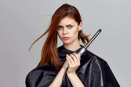 Beautiful young woman on a light gray background holds a hair curry for her hair, hairstyle.の写真素材