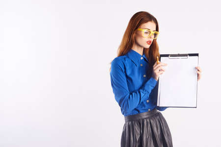 Beautiful young woman in yellow glasses holds documents on white isolated background, teacher, blank space for copy.の写真素材