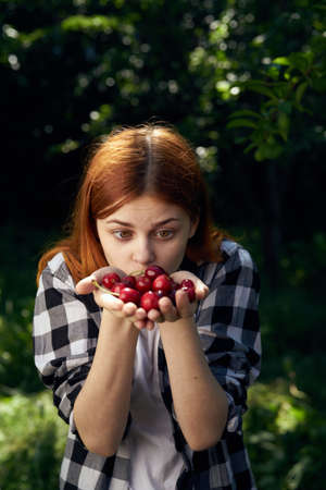 Woman holding a cherry in the garden.の写真素材