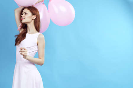 Woman in white dress holds balloons.の写真素材
