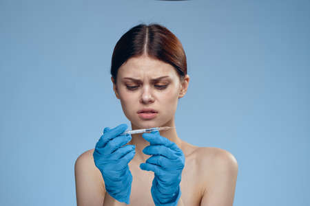 Disgust, the woman is holding a syringe in rubber gloves.の写真素材