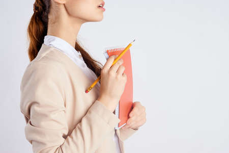 Woman holding a notebook and pencil, close-up, portrait.の写真素材