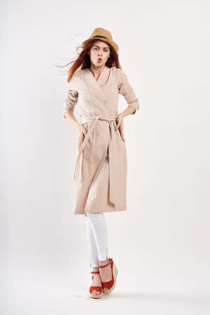 Young woman in a hat and in a coat on a white background in full growth, fashion.の写真素材