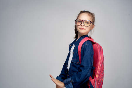 little girl with glasses with a backpack, empty space for copying.の写真素材