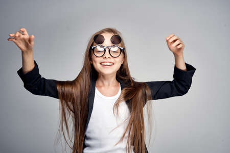 Little girl with glasses on a gray background.