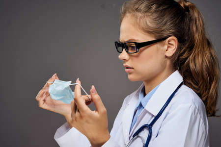 woman doctor in glasses holds a medical mask, portrait.の写真素材