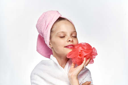 little girl in towel holding pink loofah.の写真素材