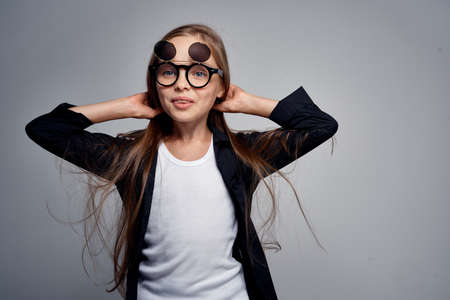 little girl straightens her hair against a gray background.の写真素材