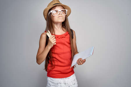girl with glasses and a hat holds notebooks, emotions.