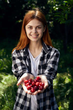 woman smiling and holding a cherry in the garden.の写真素材
