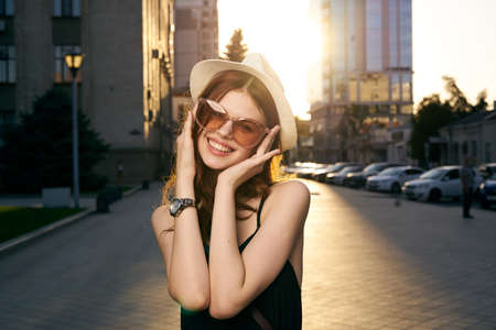 woman in a hat and sunglasses smiling in the city, portrait.の写真素材