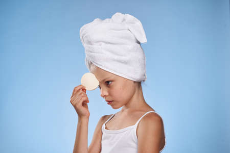 little girl with a towel on her head holds a cotton ball.の写真素材