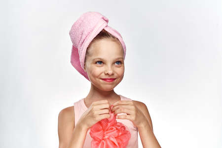 little girl with a towel on her head holds a washcloth, portrait.の写真素材