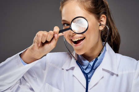 doctor holding a magnifying glass at the face, portrait.の写真素材
