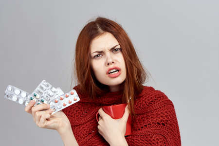 woman holding pills and mug, portrait, illness.
