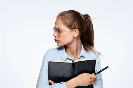 woman with glasses holds a notebook and pen, portrait.の写真素材