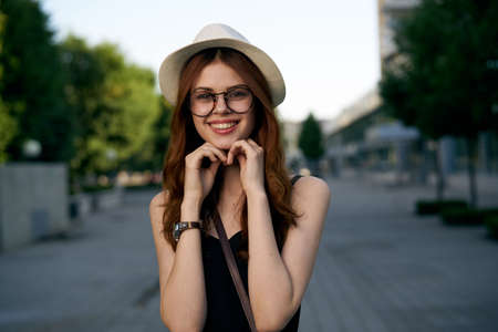 woman in glasses and wearing a hat smiling on the road in the city, portrait.の写真素材