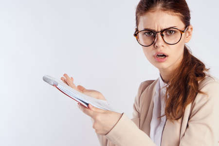teacher with glasses serious in hand holds a notebook on a light background portrait.の写真素材