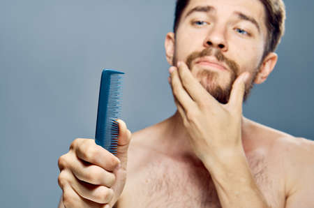 a man scratches his beard and looks at the comb.の写真素材