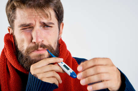 a sick man with a beard is measuring his temperature.の写真素材