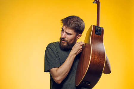 man with a guitar on a yellow background.