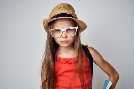 dissatisfied little girl in white glasses and wearing a hat.