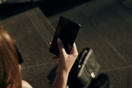 girl on the street sits on the stairs and looks at the piles smartphone.の写真素材