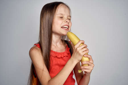 little girl in red dress does not want to eat banana.の写真素材