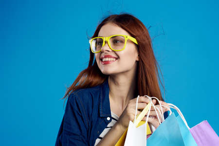 a girl in yellow glasses is happy with her purchases.の写真素材
