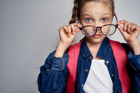 schoolgirl takes off big glasses and looks closely.の写真素材