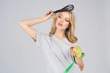 girl posing with cooking utensils and food on a light background.の写真素材