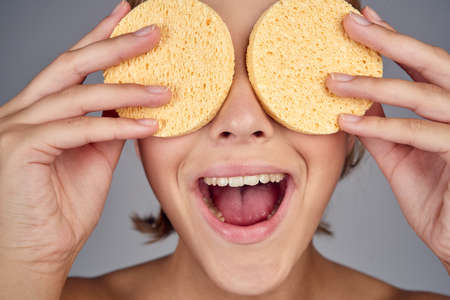 cheerful girl closed both eyes with a sponge for washing.の写真素材