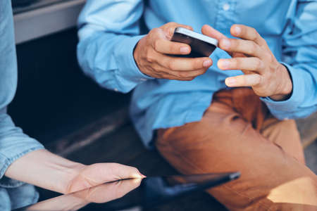 man with a phone in brown pants and a blue shirt.の写真素材