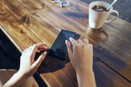 table, mug, hands and phone.の写真素材