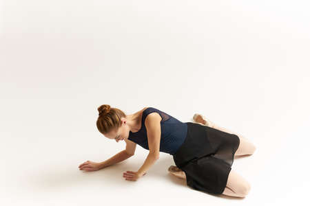 ballerina lies on the floor with hands on the ground.