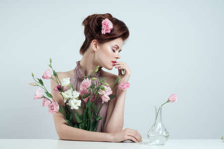 young beautiful woman with a bouquet of flowers and a vase.の写真素材
