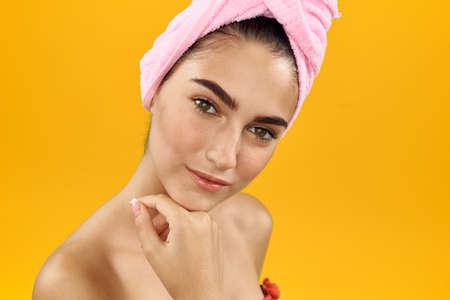 young woman with a towel on her head on a yellow background.の写真素材