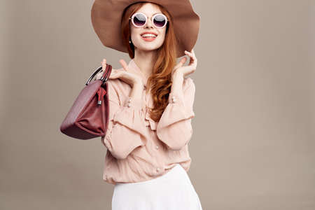 woman with glasses, hat and with a bag on a light background.の写真素材