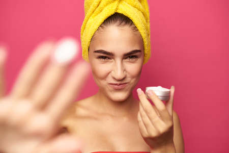 young girl with a yellow towel on her head holds a face cream.の写真素材