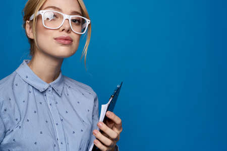 happy girl in white glasses with a phone on a blue background.の写真素材